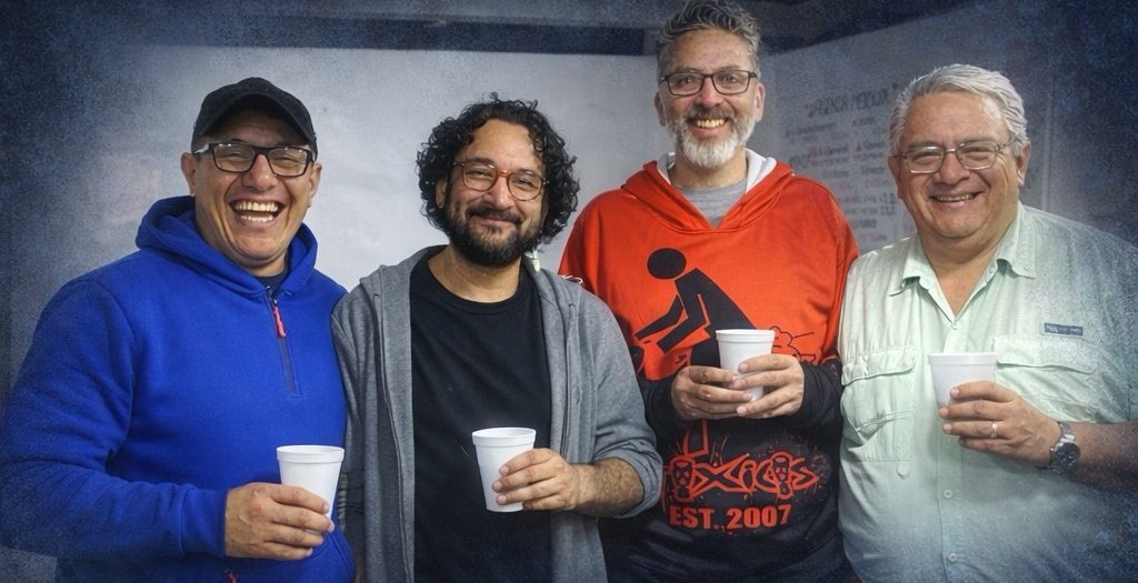 Cuatro integrantes del Círculo de Hombres de Alqhimia sonriendo con café en mano