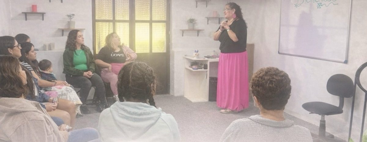 Mujeres sentadas en círculo escuchando a la facilitadora en la sede de Alqhimia